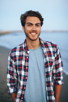 Junger Mann mit Strand im Hintergrund