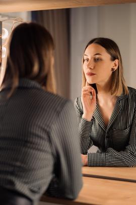 Frau schaut in den Spiegel, um ihr Selbstbewusstsein zu stärken