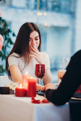 Frau beim Date im Restaurant hält sich die Hand vor den Mund