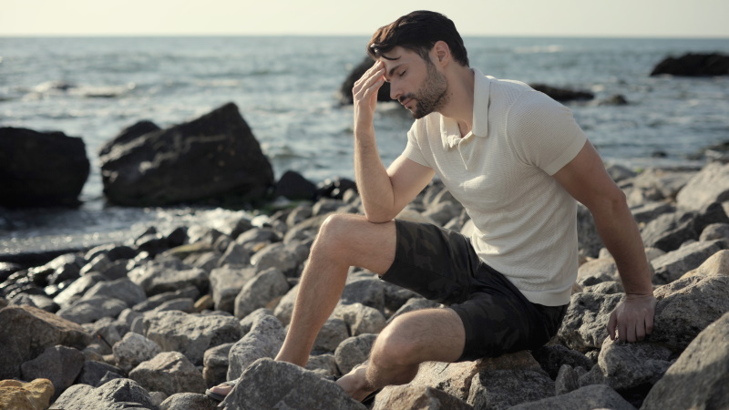 Trauriger Mann sitzt allein am Meer