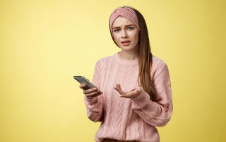 Frau schaut ratlos auf ihr Handy, weil Mann ihr nur ein Smiley schickt