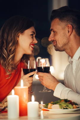 Paar beim Date mit Kerzenlicht und Wein schaut sich verliebt an