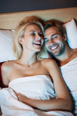 Paar liegt lachend im Bett