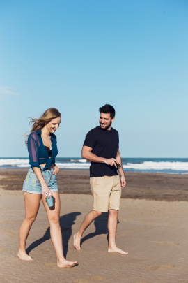 Paar spaziert am Strand in sommerlicher Kleidung