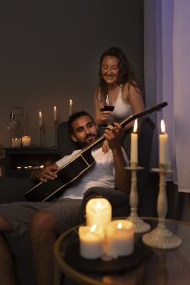 Mann spielt Frau zu Hause auf der Gitarre vor im Kerzenschein
