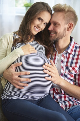 Glücklicher Mann hält Bauch der schwangeren Partnerin