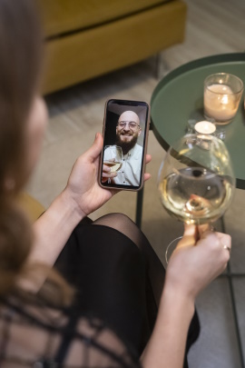 Wein trinkende Frau macht Video-Call am Handy mit älterem Mann