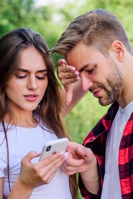 Frau wirkt abweisend zu Freund, der ihr Handy kontrollieren will