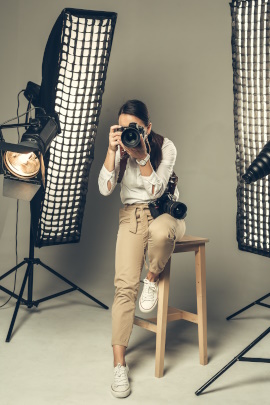Fotografin sitzt im Studio vor Scheinwerfern und fotografiert