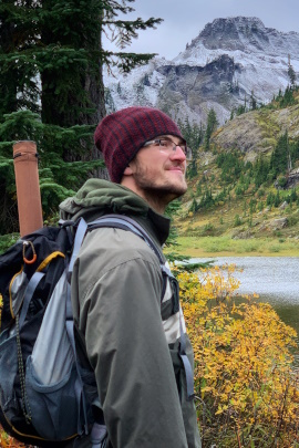 Lächelnder Mann steht bei Wanderung in der Natur