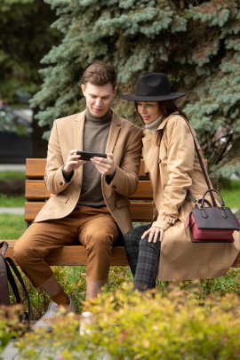Paar sitzt mit Smartphone auf der Parkbank