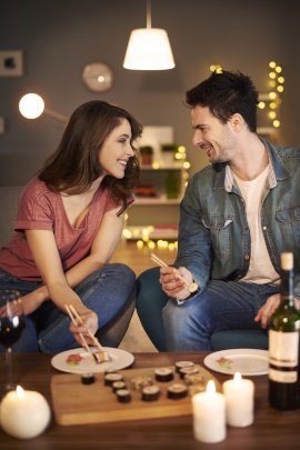 Paar sitzt beim Date zu Hause mit Rotwein und isst Sushi