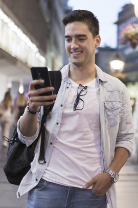 Mann in der Stadt schaut lachend aufs Smartphone
