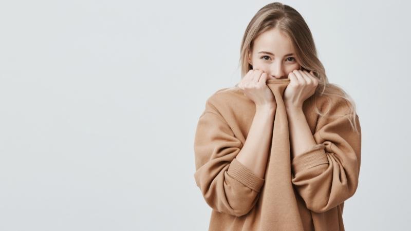 Schüchterne Frau versteckt sich in ihrem Pullover
