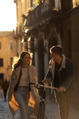 Mann mit Fahrrad läuft neben Frau durch die Stadt