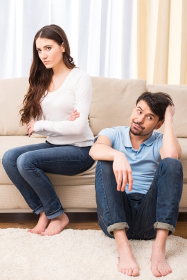 Mann und Frau sitzen zu Hause distanziert auf dem Sofa