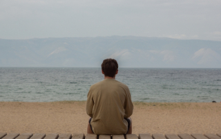 Mann sitzt alleine am Strand und sehnt sich nach Liebe
