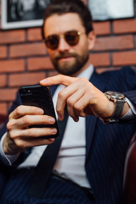 Mann mit Sonnenbrille schaut aufs Handy