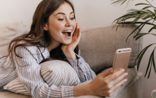 Frau schaut begeistert aufs Handy