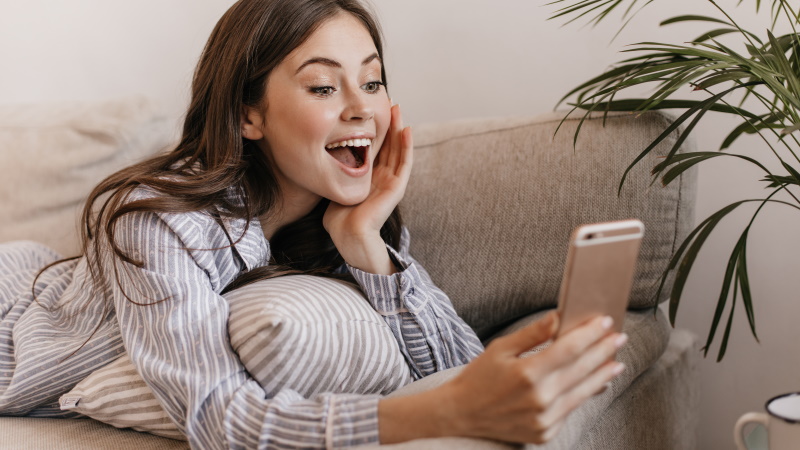 Frau schaut begeistert aufs Handy