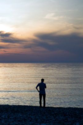 Mann mit Trennungsschmerz blickt abends aufs Meer