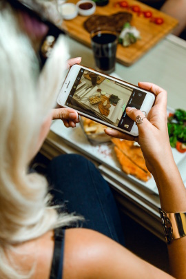 Frau macht Foto von ihrem Essen in der Küche