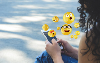 Frau, aus deren Handy gelbe lustige Smileys aufsteigen