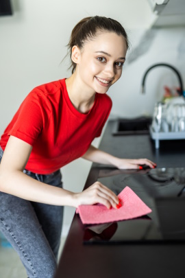 Lächelnde Frau reinigt die Küchenarbeitsplatte mit einem Tuch