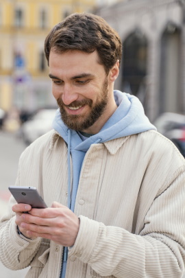 Verliebter Mann schaut lächelnd aufs Handy