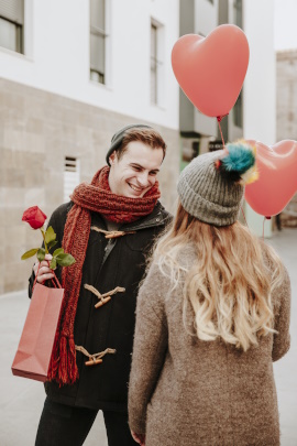 Romantischer Mann gibt Frau eine Rose auf der Straße