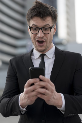 Mann im Anzug schaut verzweifelt schreiend aufs Smartphone