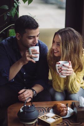 Paar sitzt lächelnd am Tisch und trinkt Kaffee