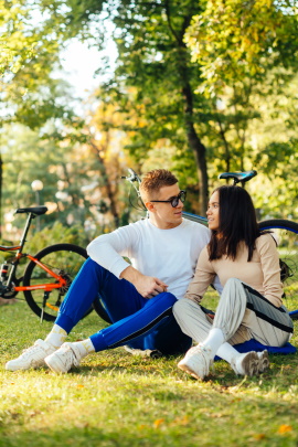 Paar mit Fahrrädern sitzt während Gespräch im Park