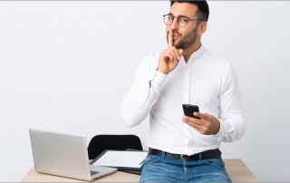 Mann mit Handy im Büro schaut geheimnisvoll