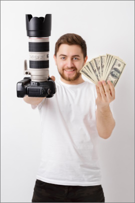 Grinsender Fotograf hält Kamera und Geldscheine in den Händen