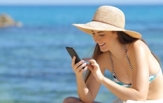 Frau mit Smartphone am Strand liest Tinder-Bio