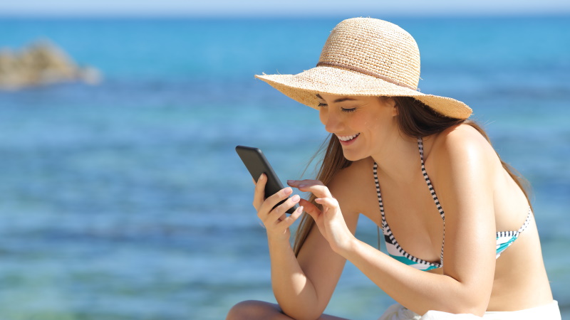 Frau mit Smartphone am Strand liest Tinder-Bio