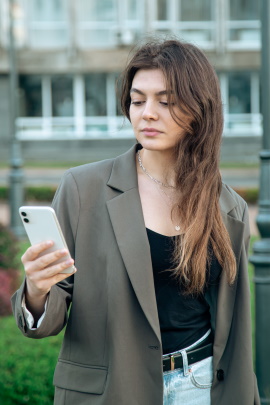 Frau vor Gebäude schaut kritisch aufs Handy