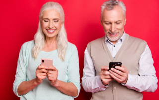 Älteres Paar schaut lachend auf Smartphones