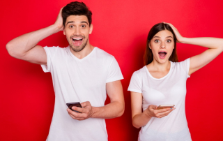 Schockiert lachendes Paar mit Smartphones