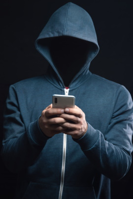 Anonymer Mann mit Kapuzenpullover und Handy