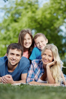 Familie mit zwei Kindern liegt lächelnd im Gras