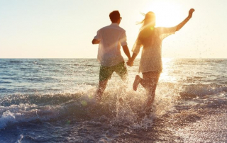 Mann und Frau halten Händchen und laufen am Strand entlang