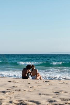 Mann und Frau sitzen flirtend am Strand