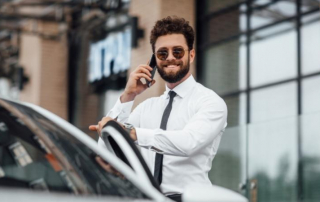 Attraktiver Chef steigt lächelnd in sein Auto