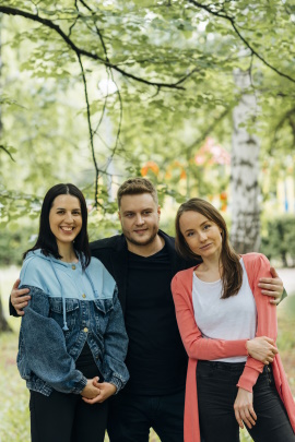 Junger Mann steht mit zwei Frauen im Park