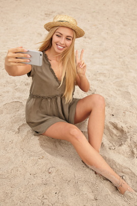Lächelnde Frau macht Selfie am Strand