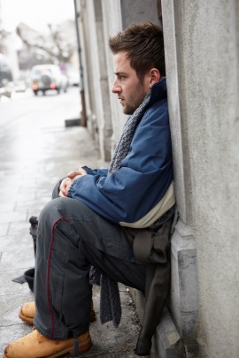 Single-Mann sitzt einsam vor dem Haus