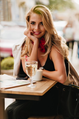Frau sitzt lächelnd am Tisch im Café