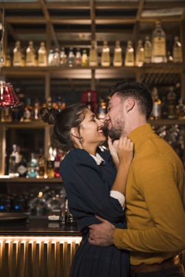 Paar in einer Bar umarmt sich lachend kurz vorm Kuss